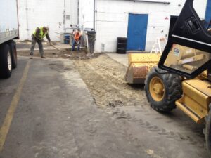 Two men working on an asphalt parking lot.